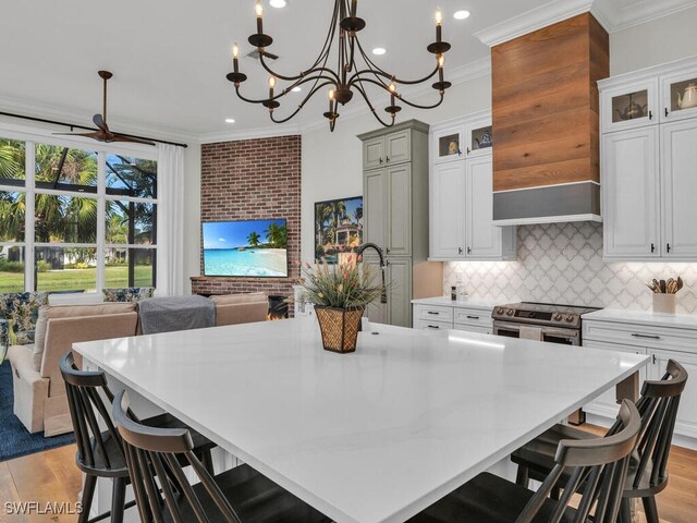 kitchen featuring stainless steel electric range oven, custom exhaust hood, a large island, crown molding, and light wood-type flooring