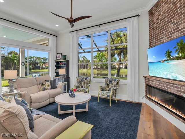 living room with hardwood / wood-style flooring, ornamental molding, a brick fireplace, and plenty of natural light