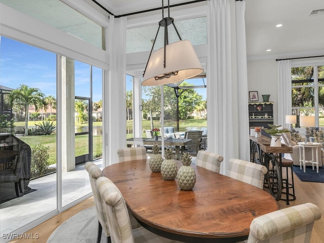 dining space with ornamental molding and light wood-type flooring