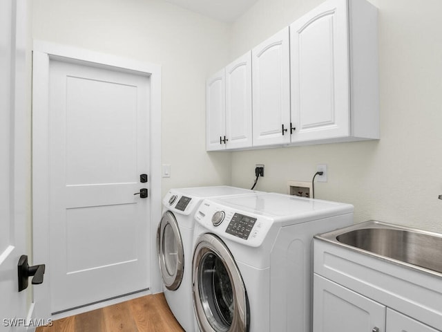 clothes washing area featuring cabinets, light wood-type flooring, sink, and independent washer and dryer