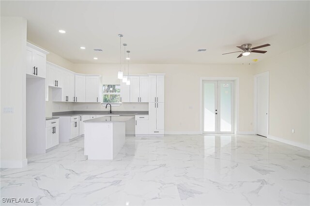 kitchen with a kitchen island, decorative light fixtures, and white cabinets