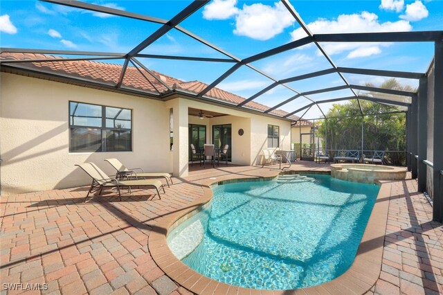 view of swimming pool with an in ground hot tub, ceiling fan, glass enclosure, and a patio