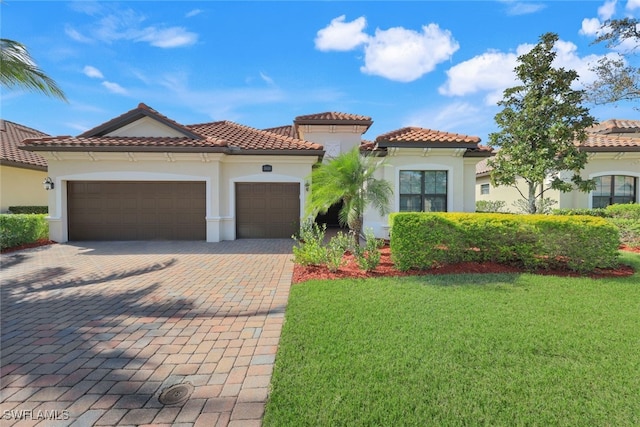 mediterranean / spanish home featuring a front lawn and a garage