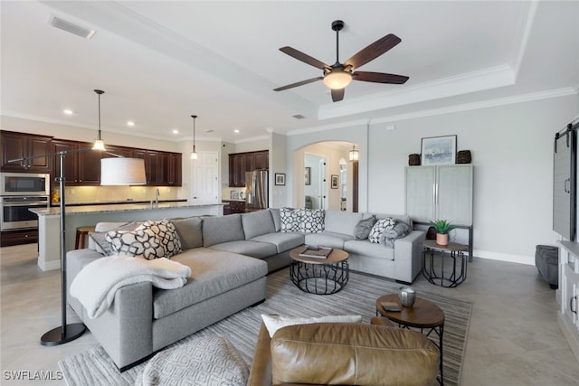 living room with ceiling fan, a raised ceiling, and ornamental molding