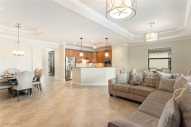 tiled living room with sink, crown molding, and a tray ceiling