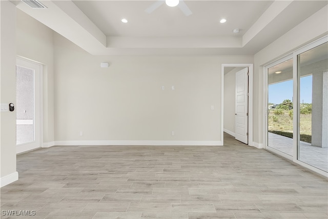 spare room featuring light hardwood / wood-style flooring, a raised ceiling, and ceiling fan