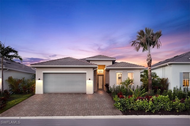 view of front of property with an attached garage, decorative driveway, and stucco siding