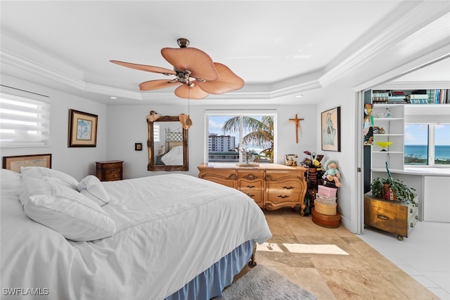 bedroom with a water view, ceiling fan, a raised ceiling, and multiple windows