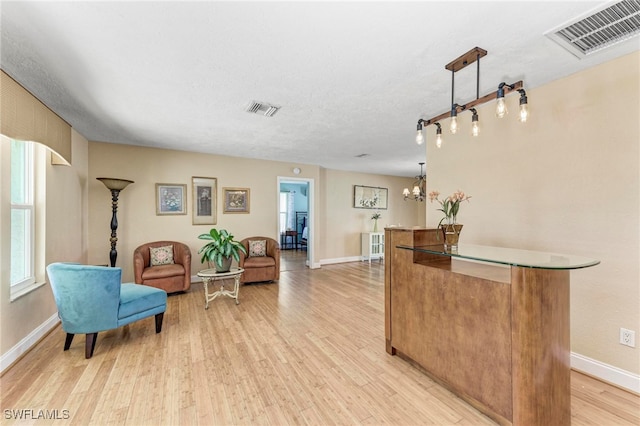 interior space featuring a notable chandelier, a textured ceiling, and light wood-type flooring