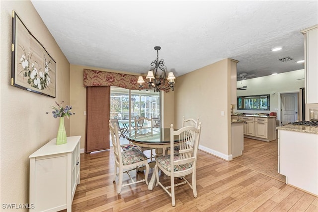 dining area with a notable chandelier, a textured ceiling, and light wood-type flooring