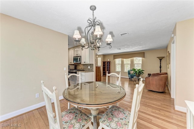 dining area featuring light hardwood / wood-style floors, an inviting chandelier, and a textured ceiling