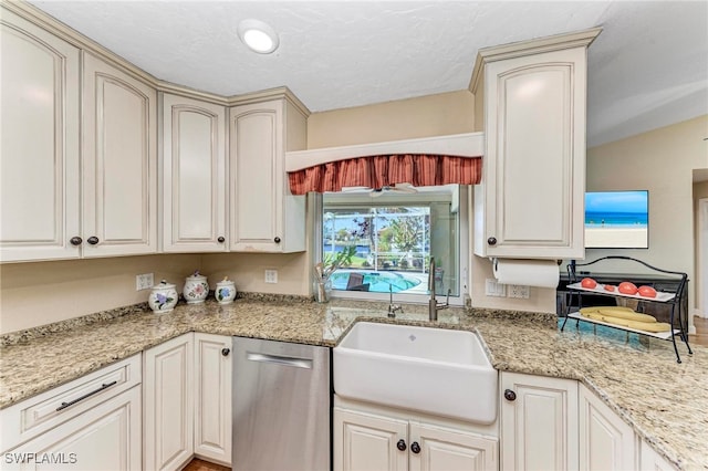 kitchen featuring cream cabinets, light stone counters, a textured ceiling, dishwasher, and sink