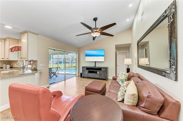 living room with lofted ceiling, sink, light wood-type flooring, and ceiling fan