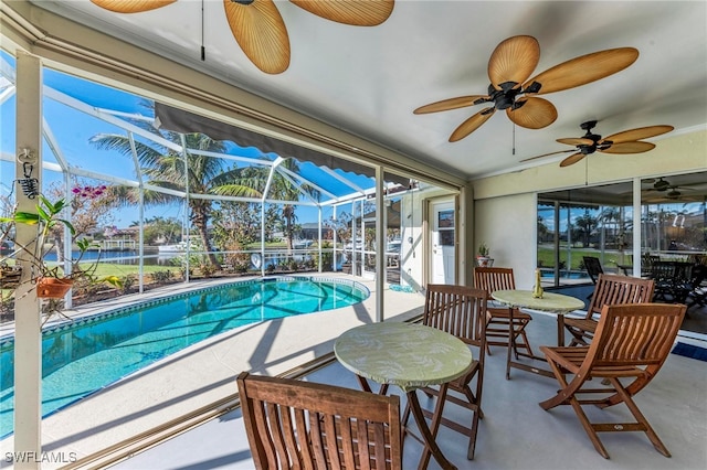 view of swimming pool with a water view, a patio, glass enclosure, and ceiling fan