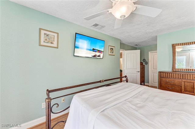 bedroom with a textured ceiling, light wood-type flooring, and ceiling fan