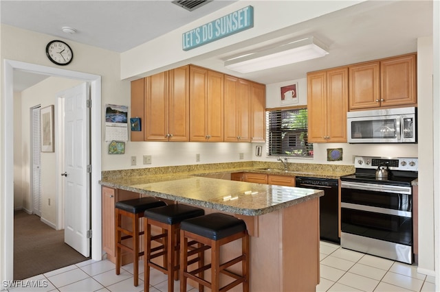 kitchen featuring kitchen peninsula, appliances with stainless steel finishes, a kitchen breakfast bar, light stone counters, and light tile patterned floors