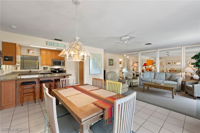 dining area with light tile patterned floors, ceiling fan with notable chandelier, and sink