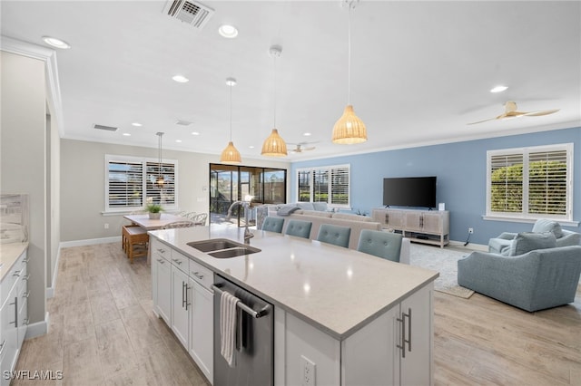 kitchen featuring white cabinetry, sink, hanging light fixtures, a center island with sink, and light wood-type flooring