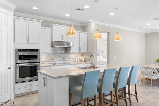 kitchen with pendant lighting, a center island with sink, white cabinets, sink, and black electric cooktop