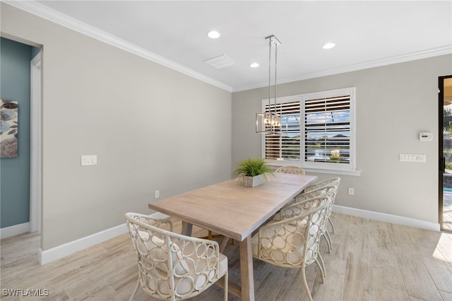 dining room with crown molding and light hardwood / wood-style floors