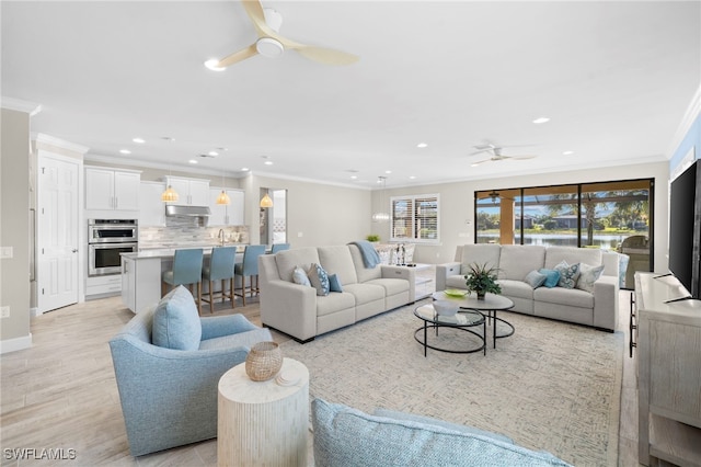 living room with crown molding, ceiling fan, and light wood-type flooring