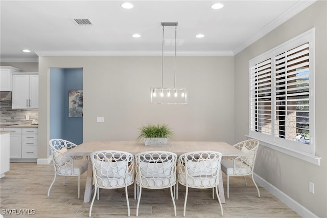 dining area with light wood-type flooring and ornamental molding