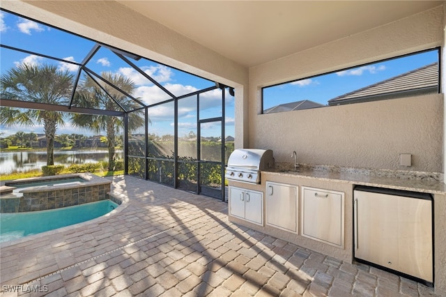 view of patio with glass enclosure, grilling area, an outdoor kitchen, a water view, and an in ground hot tub