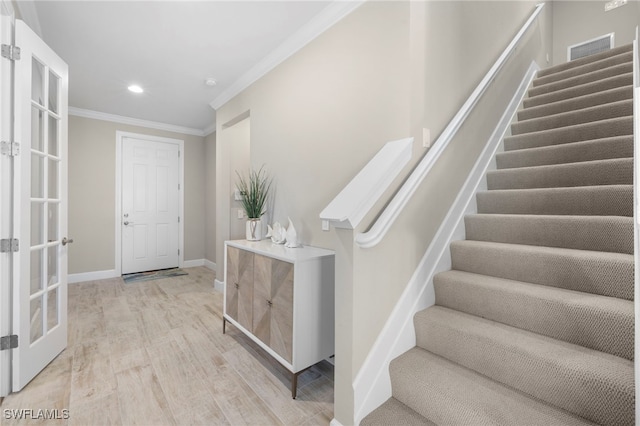 entrance foyer with french doors, light hardwood / wood-style floors, and crown molding