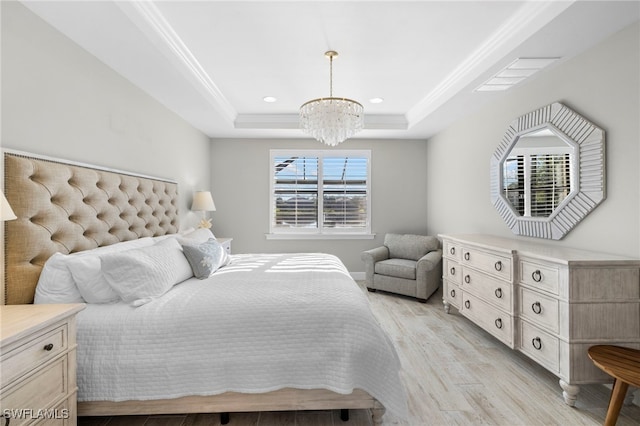 bedroom with a notable chandelier, light hardwood / wood-style floors, a raised ceiling, and ornamental molding