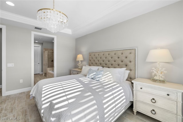 bedroom featuring ensuite bath, a raised ceiling, crown molding, light hardwood / wood-style flooring, and a notable chandelier