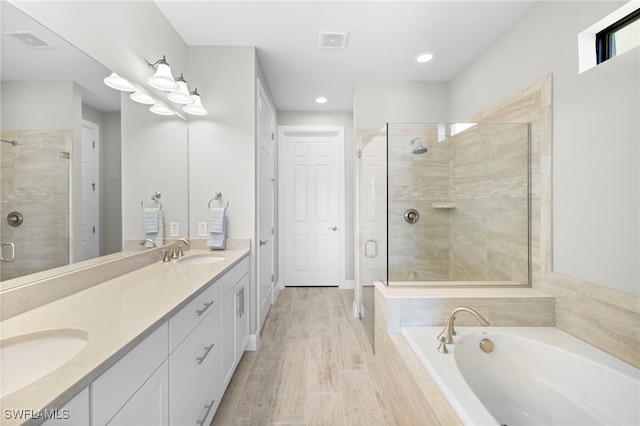 bathroom with hardwood / wood-style floors, vanity, and separate shower and tub