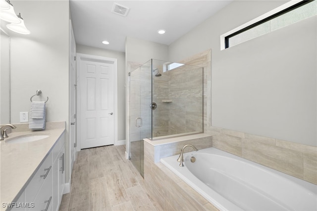 bathroom featuring hardwood / wood-style flooring, vanity, and shower with separate bathtub