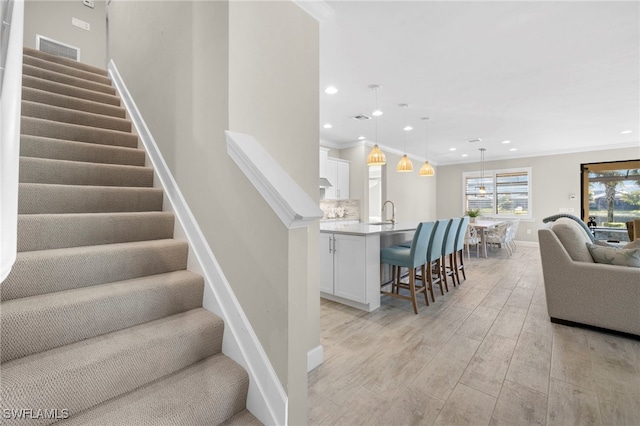 stairway with wood-type flooring and crown molding