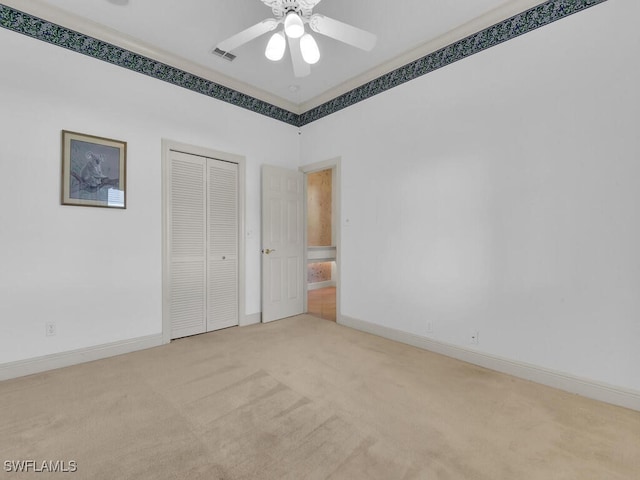 unfurnished bedroom featuring ceiling fan, a closet, and light colored carpet