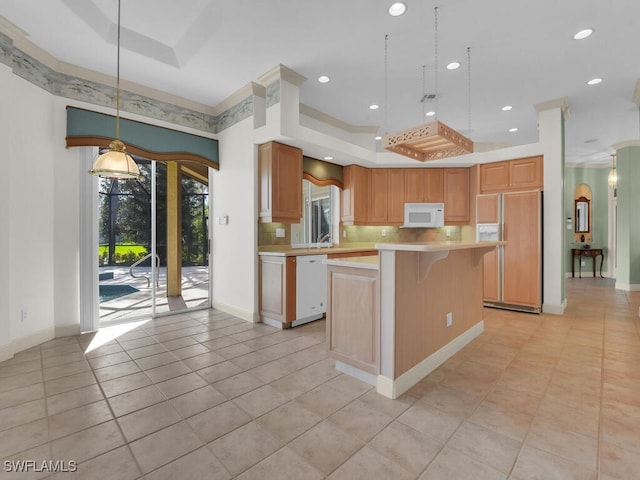 kitchen featuring a tray ceiling, light tile patterned floors, a kitchen island, and white appliances