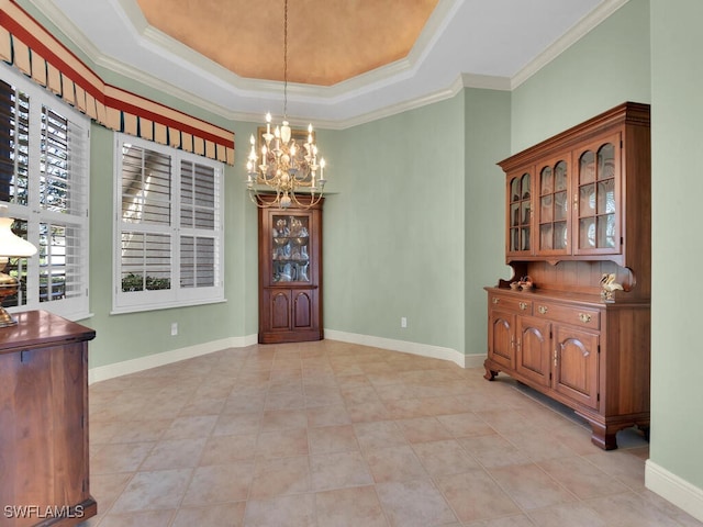 foyer with a raised ceiling, crown molding, and a chandelier