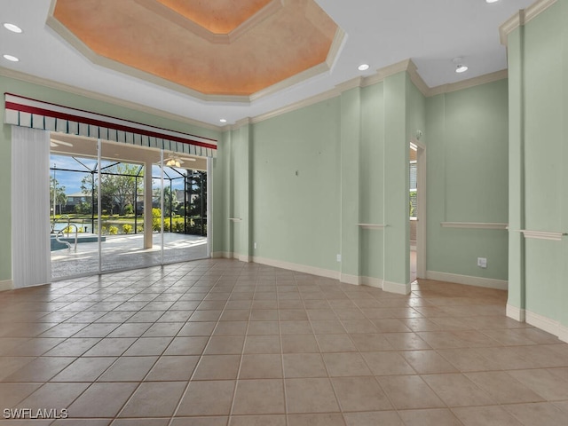 tiled empty room featuring a tray ceiling and crown molding