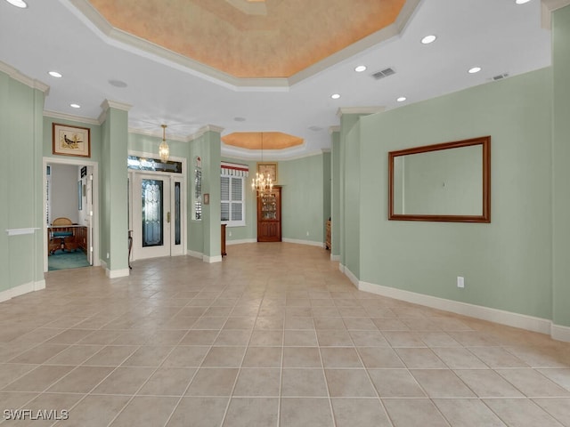 tiled empty room with a chandelier, a raised ceiling, and ornamental molding