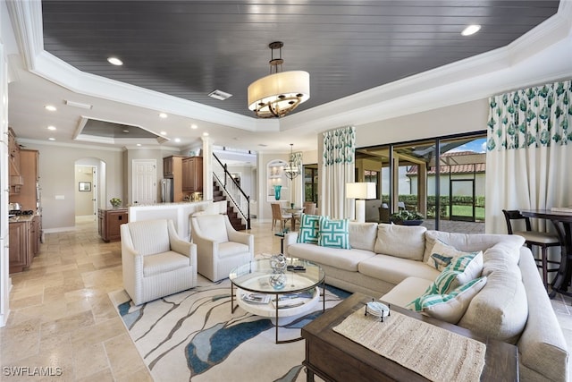 living room featuring a raised ceiling, a notable chandelier, and ornamental molding