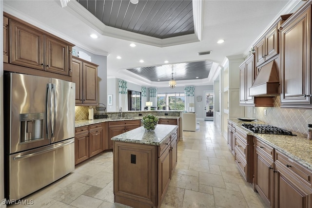 kitchen featuring kitchen peninsula, stainless steel fridge, ornamental molding, a tray ceiling, and pendant lighting