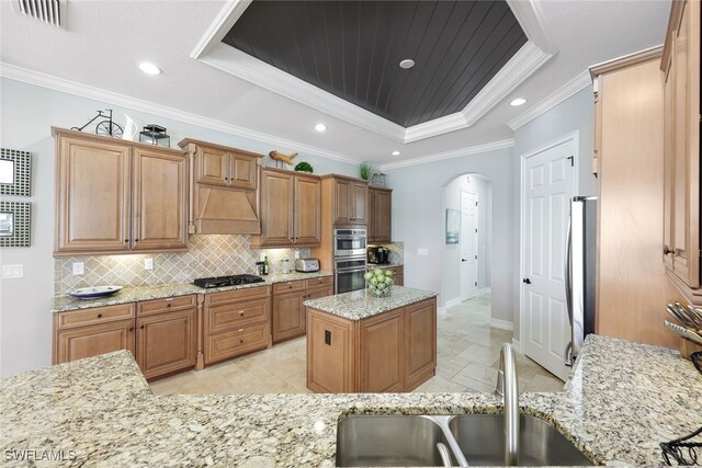 kitchen featuring custom exhaust hood, a raised ceiling, light stone countertops, ornamental molding, and appliances with stainless steel finishes