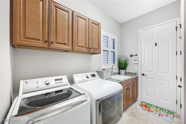 clothes washing area with cabinets, sink, and washing machine and clothes dryer