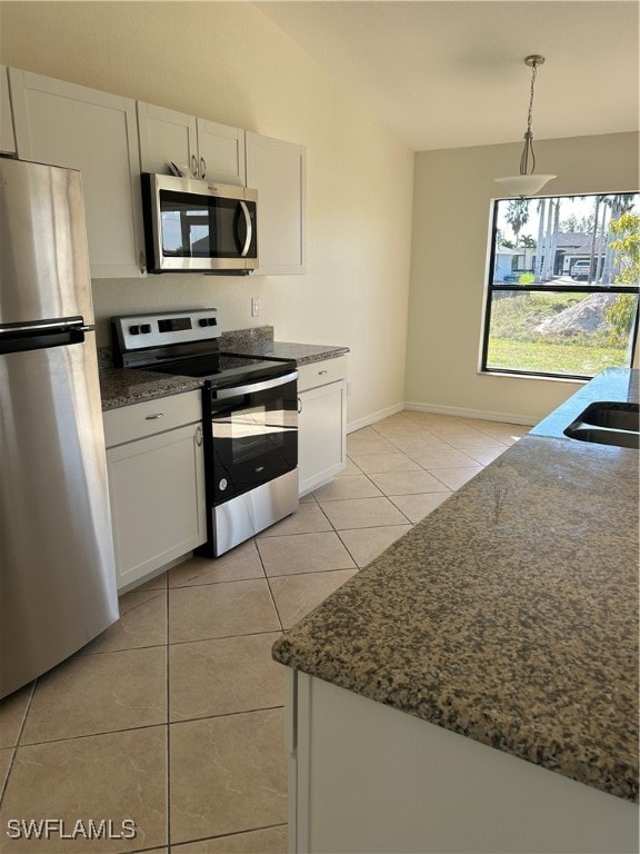 kitchen featuring white cabinetry, stainless steel appliances, light tile patterned floors, and hanging light fixtures