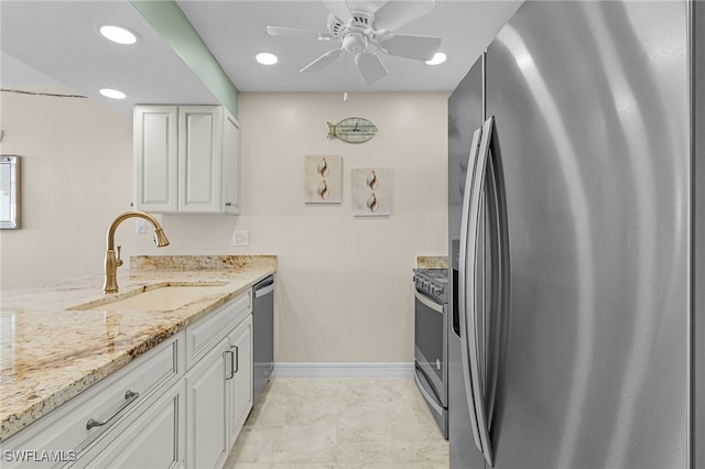 kitchen featuring ceiling fan, appliances with stainless steel finishes, white cabinetry, light stone countertops, and sink