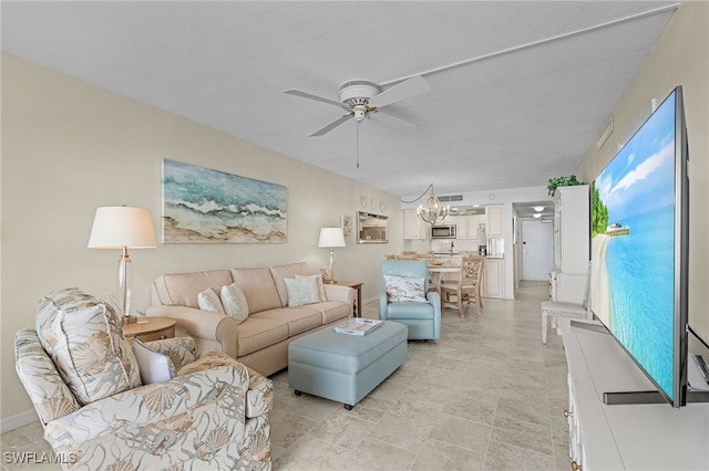 living room featuring a textured ceiling and ceiling fan with notable chandelier