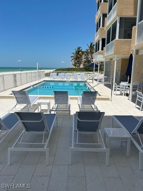 view of pool featuring a patio area, a view of the beach, and a water view