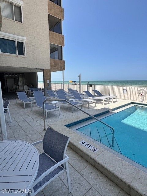 view of pool featuring a patio area, a view of the beach, and a water view