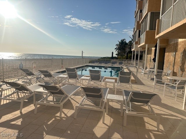 view of pool with a patio, a view of the beach, and a water view