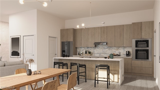 kitchen with stainless steel refrigerator with ice dispenser, sink, multiple ovens, a breakfast bar, and light hardwood / wood-style flooring