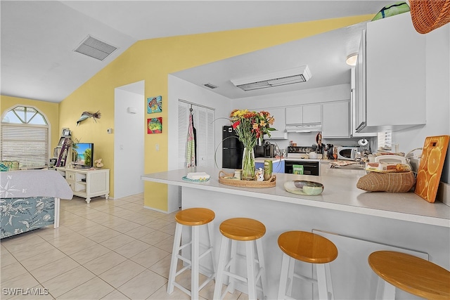 kitchen featuring kitchen peninsula, a kitchen breakfast bar, white appliances, white cabinetry, and lofted ceiling